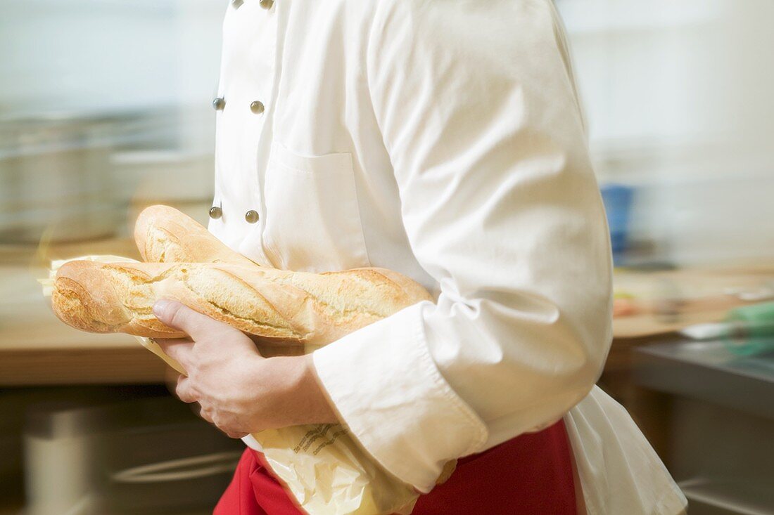 Koch läuft mit Baguettes durch Küche