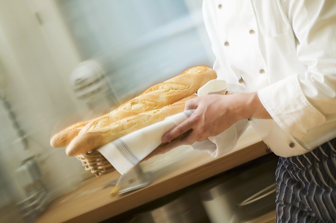 Chef hurrying through kitchen with baguettes
