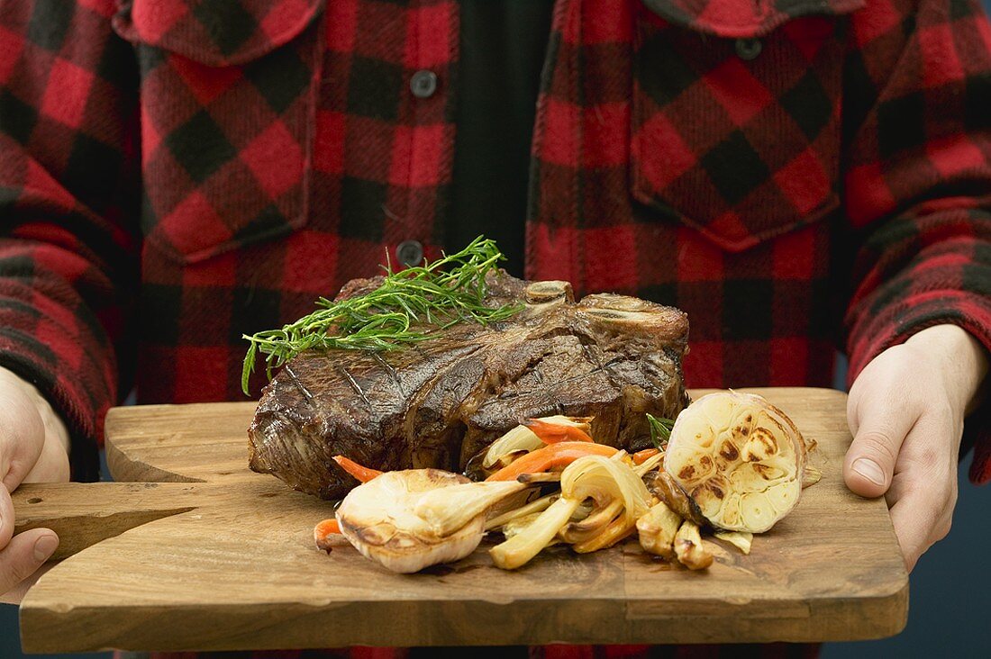 Man serving grilled T-bone steak on chopping board
