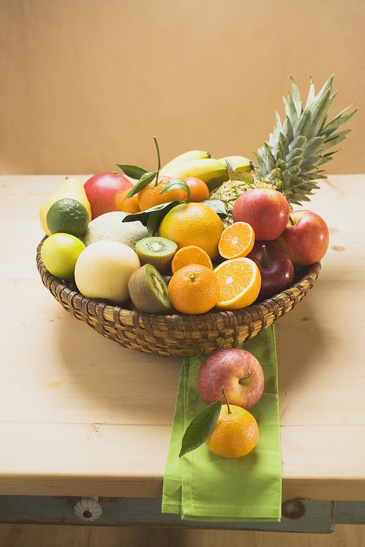 An assortment of fresh fruit in a basket on a wooden table