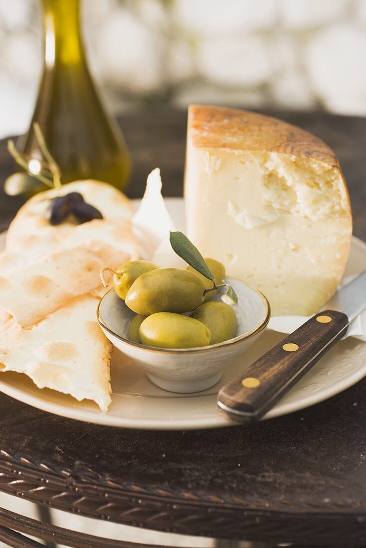 Käse, grüne Oliven, Cracker und Olivenöl auf Tisch