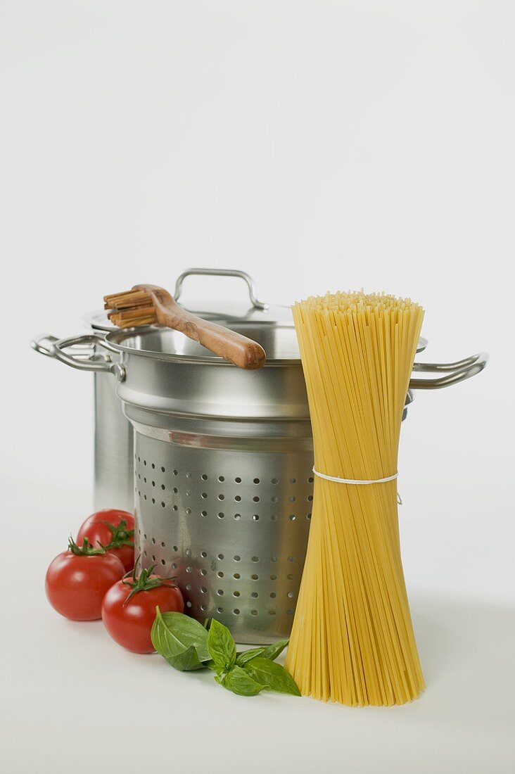 Spaghetti, Kochtöpfe, Spaghettiheber, Tomaten und Basilikum