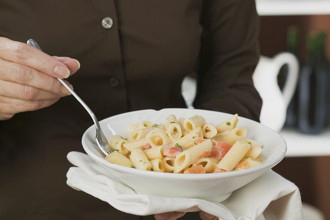 Woman eating penne with tomatoes