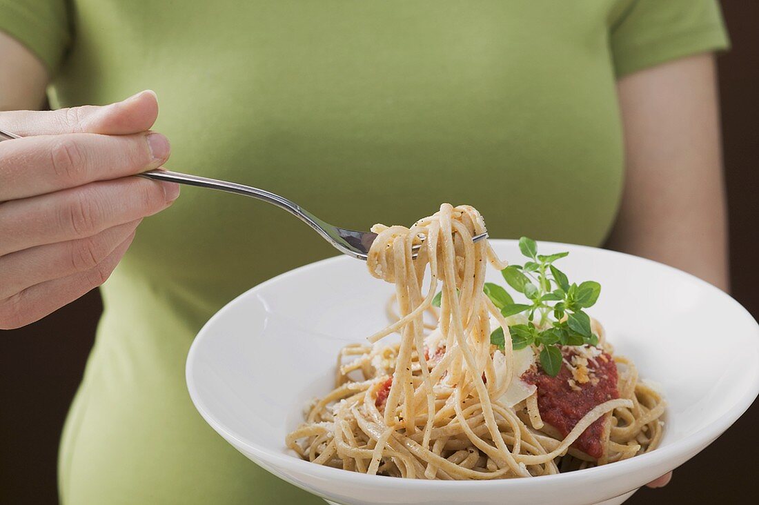 Frau isst Linguine mit Tomatensauce