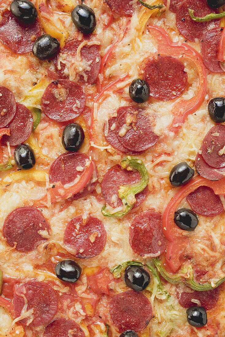 Pizza mit Peperoniwurst, Paprika und Oliven (bildfüllend)