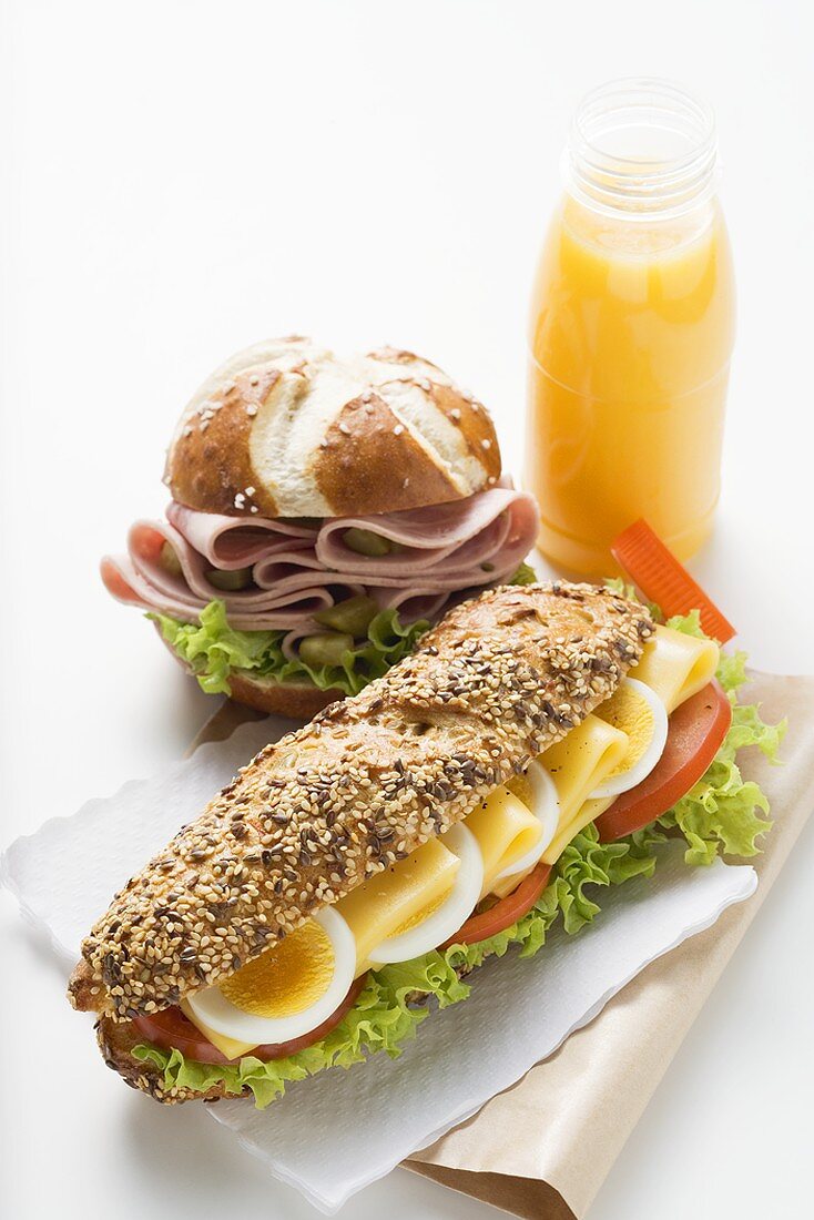 Egg in granary roll, sausage in pretzel roll, orange juice