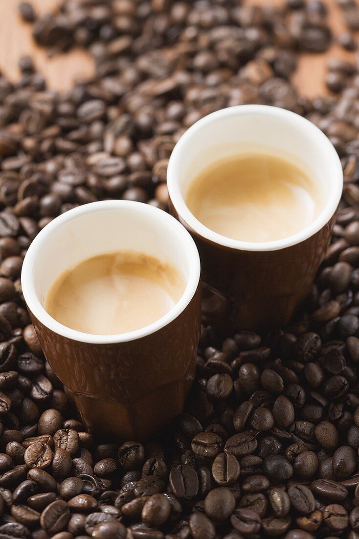 Two cups of espresso on coffee beans
