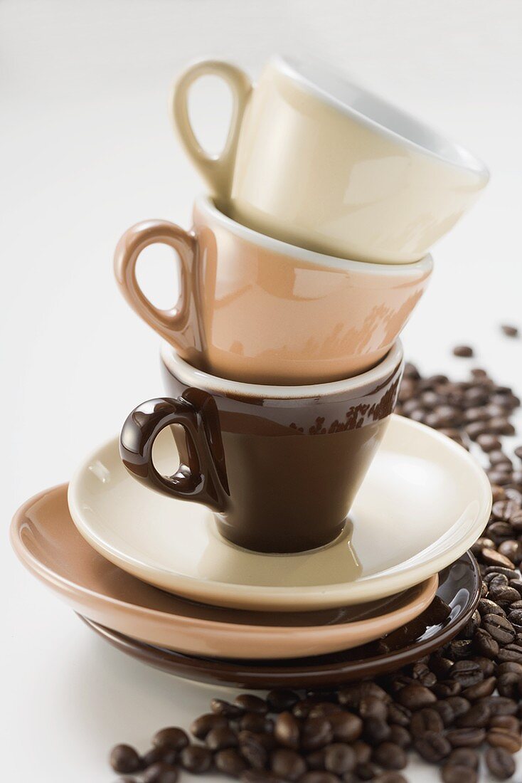 Three espresso cups and saucers, stacked, coffee beans