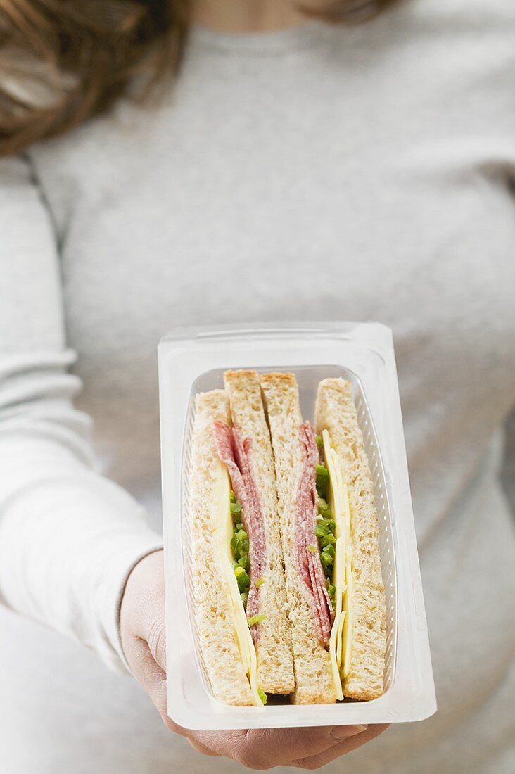 Woman holding pack of sandwiches