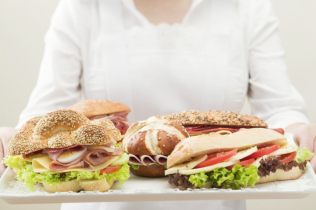 Kellnerin hält Tablett mit verschiedenen Sandwiches