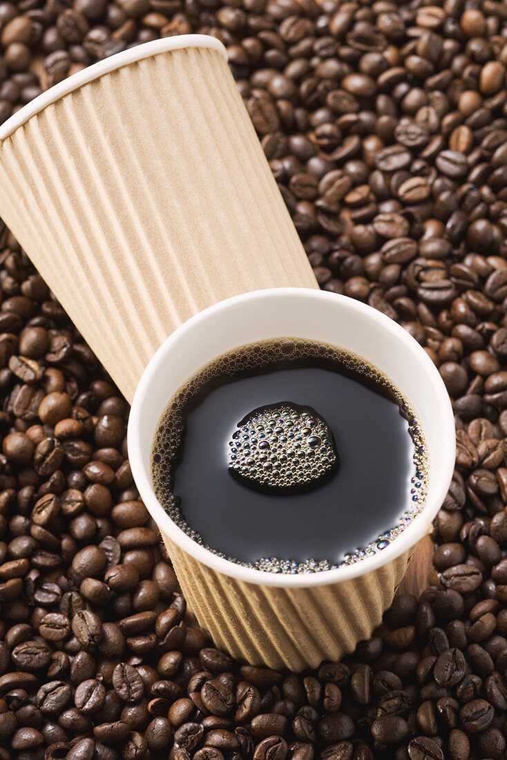 Schwarzer Kaffee im Pappbecher auf Kaffeebohnen