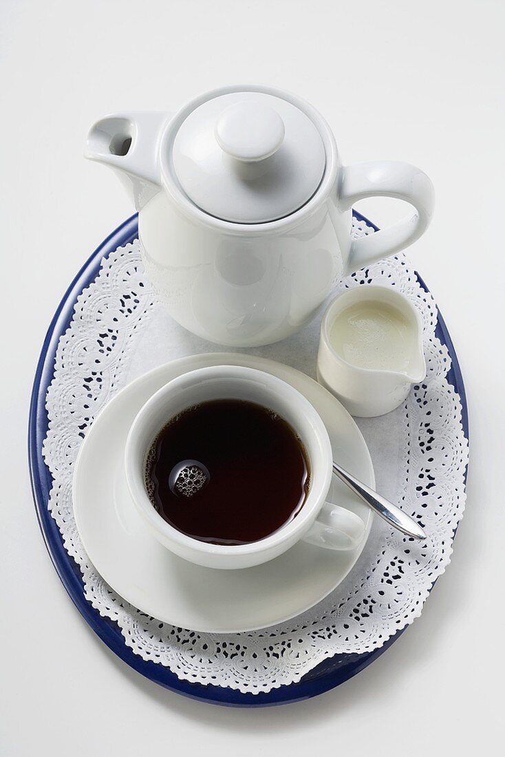 Schwarzer Kaffee in weisser Tasse, Sahne, Kaffeekanne