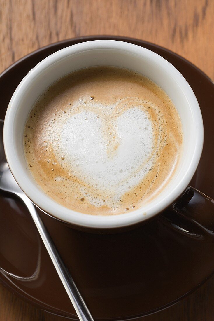 Espresso with milk froth in shape of heart (overhead view)