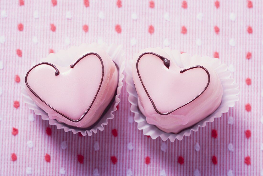 Zwei herzförmige rosa Petit fours (Draufsicht)