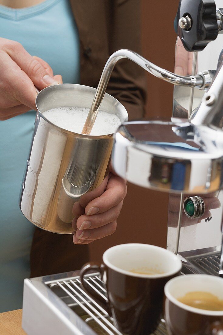 Frau schäumt Milch auf mit Espressomaschine