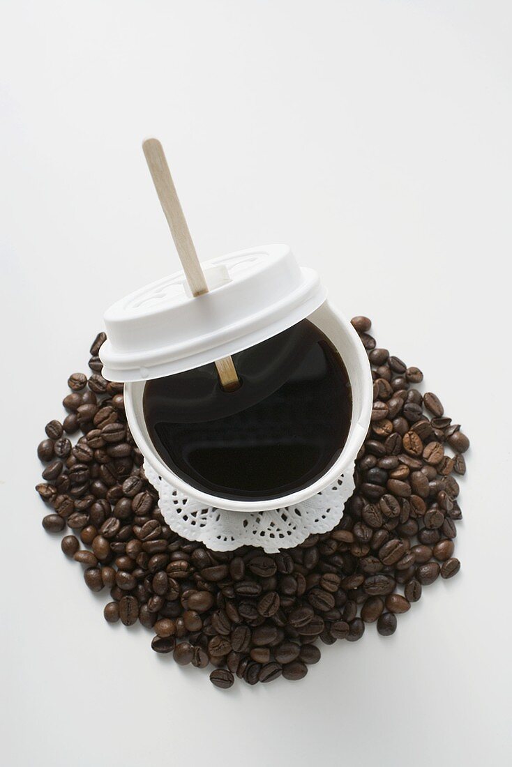 Schwarzer Kaffee im Becher auf Kaffeebohnen