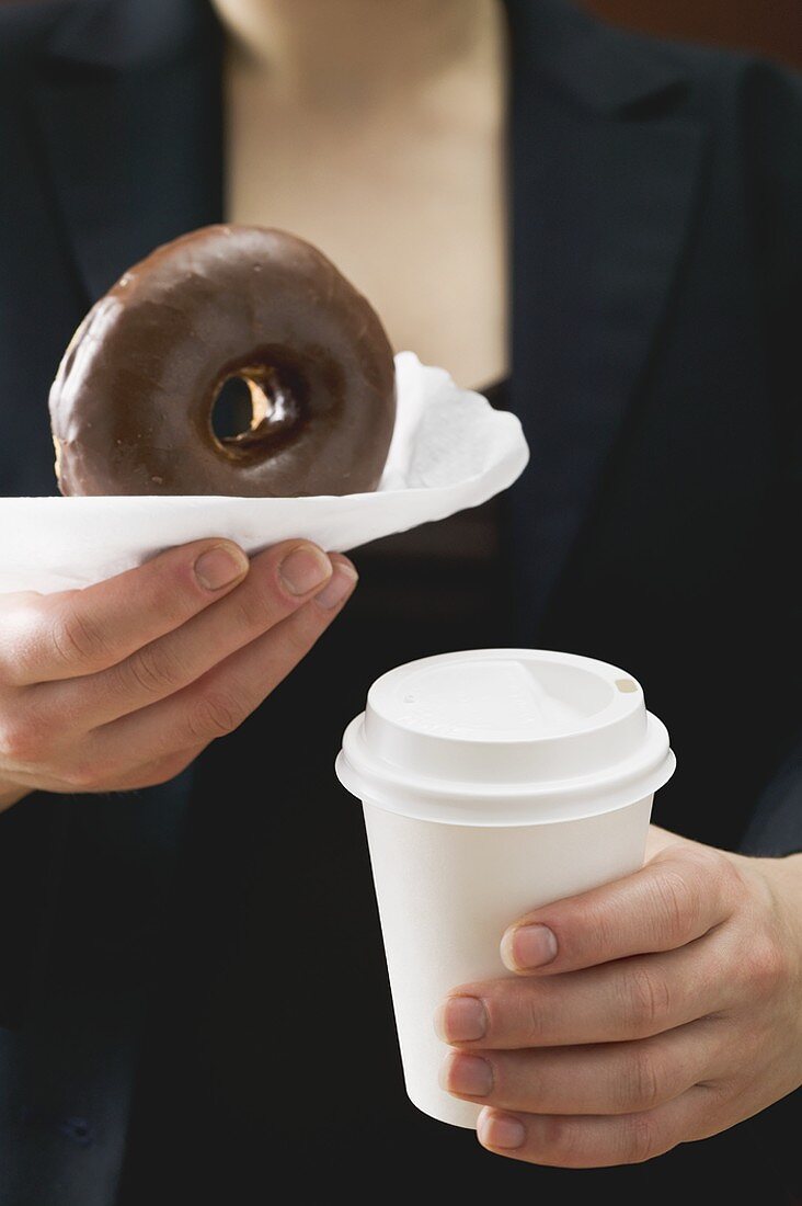 Frau hält Doughnut und Kaffeebecher