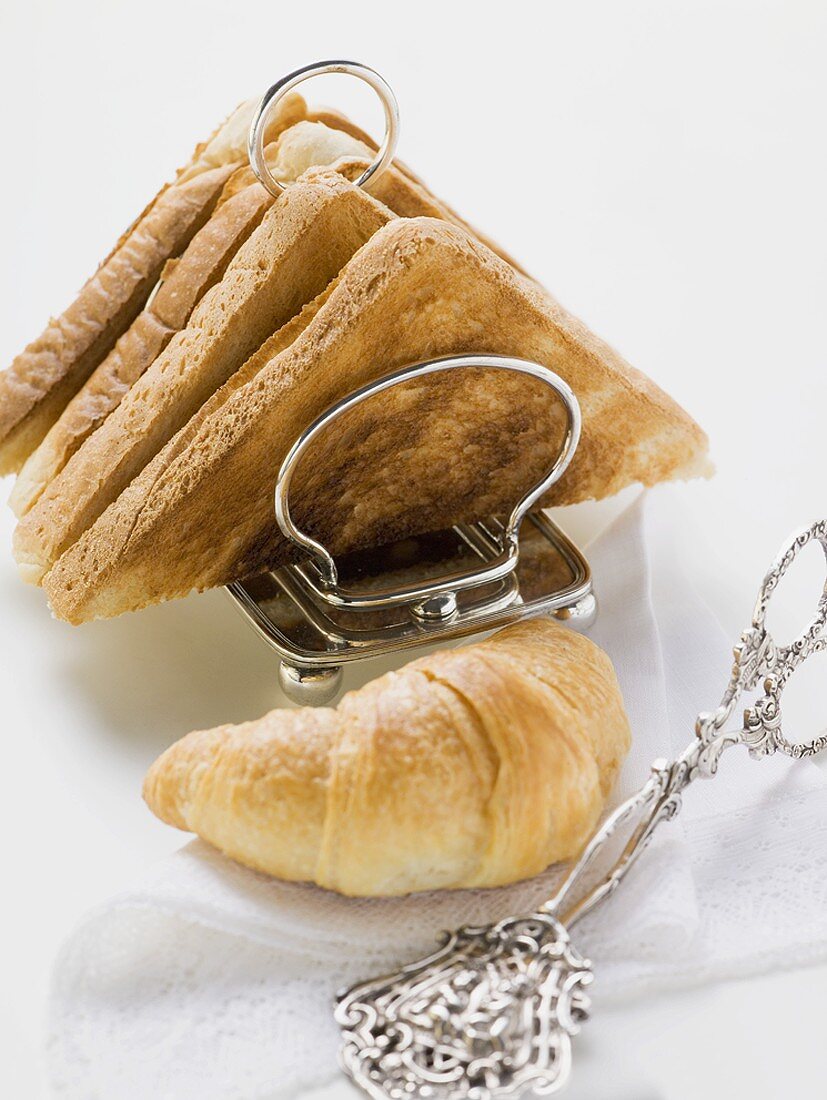 Toast in toast rack, croissant and pastry tongs