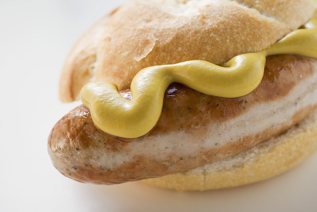 Sausage (bratwurst) with mustard in bread roll