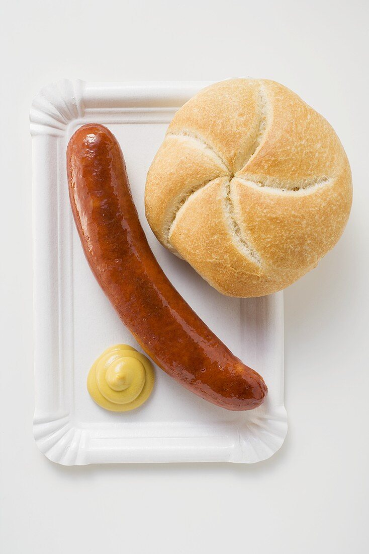 Bratwurst mit Senf und Brötchen auf Pappteller