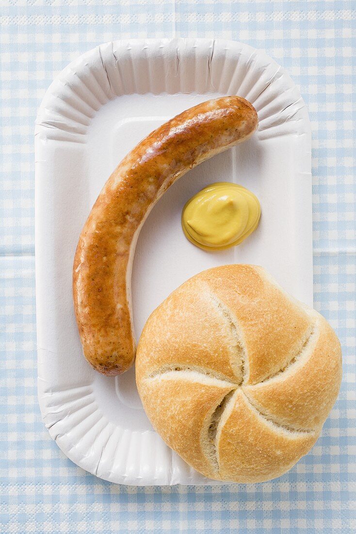 Bratwürstchen mit Senf und Brötchen auf Pappteller