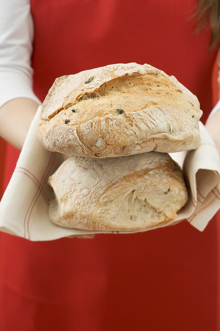 Frau hält zwei frisch gebackene Brotlaibe