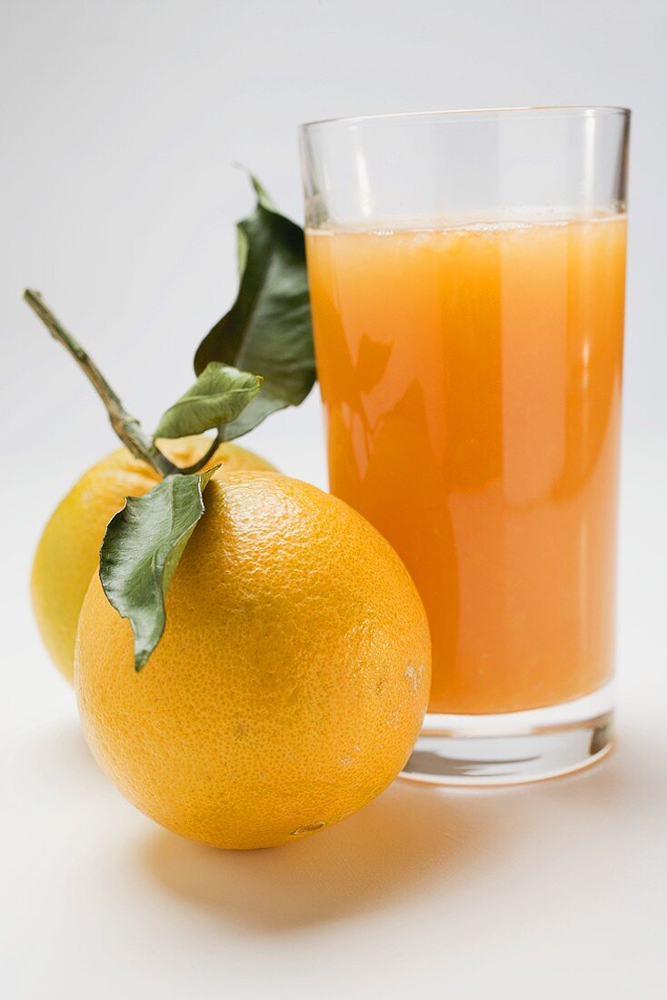 Glas Orangensaft und zwei Orangen