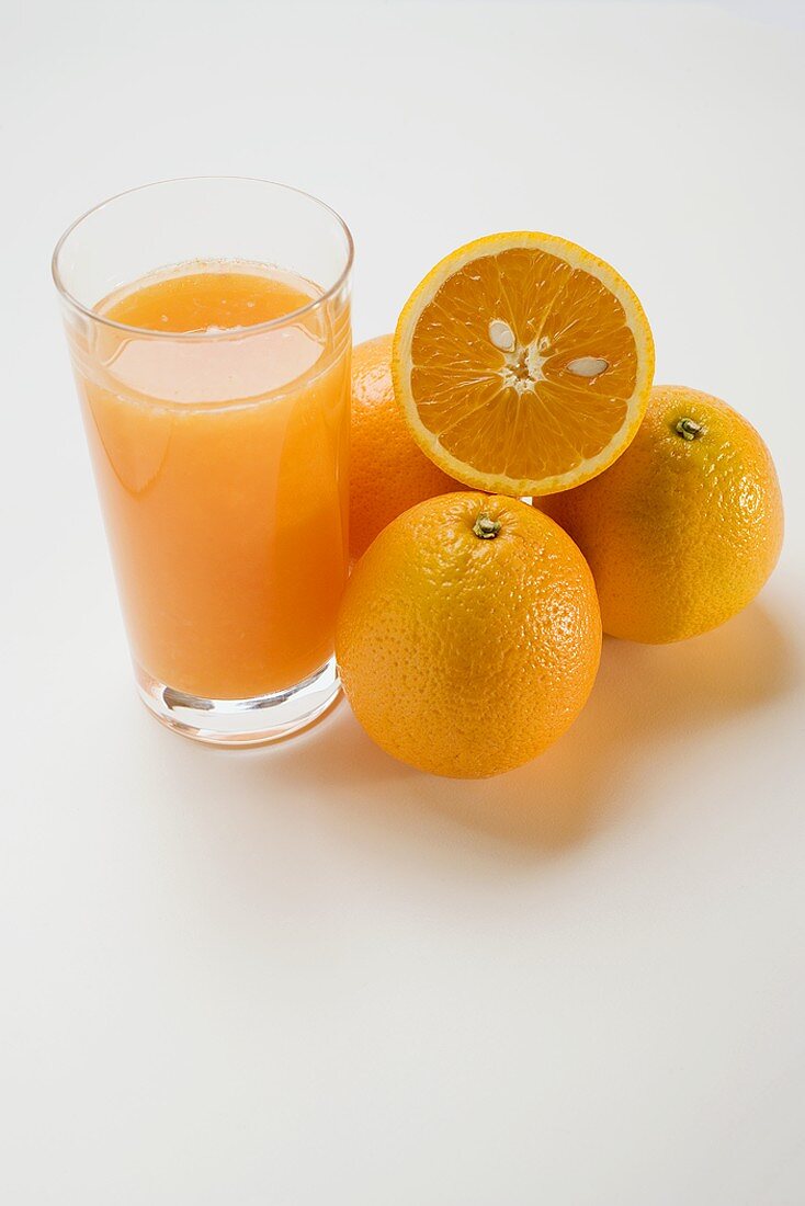 Glass of orange juice and several oranges