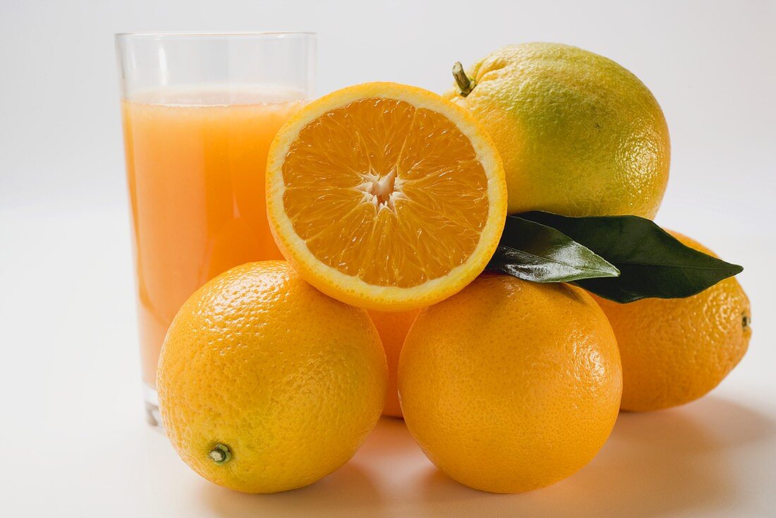 Glas Orangensaft und mehrere Orangen