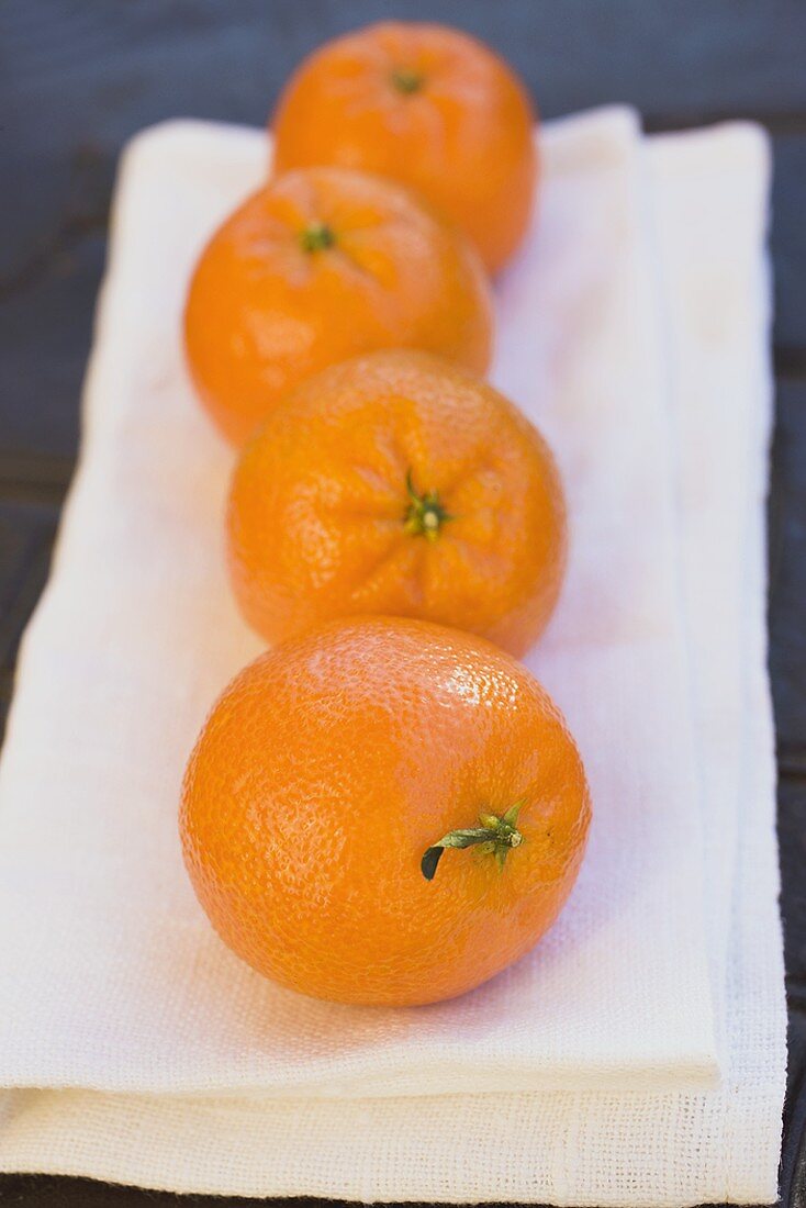 Four clementines on white cloth