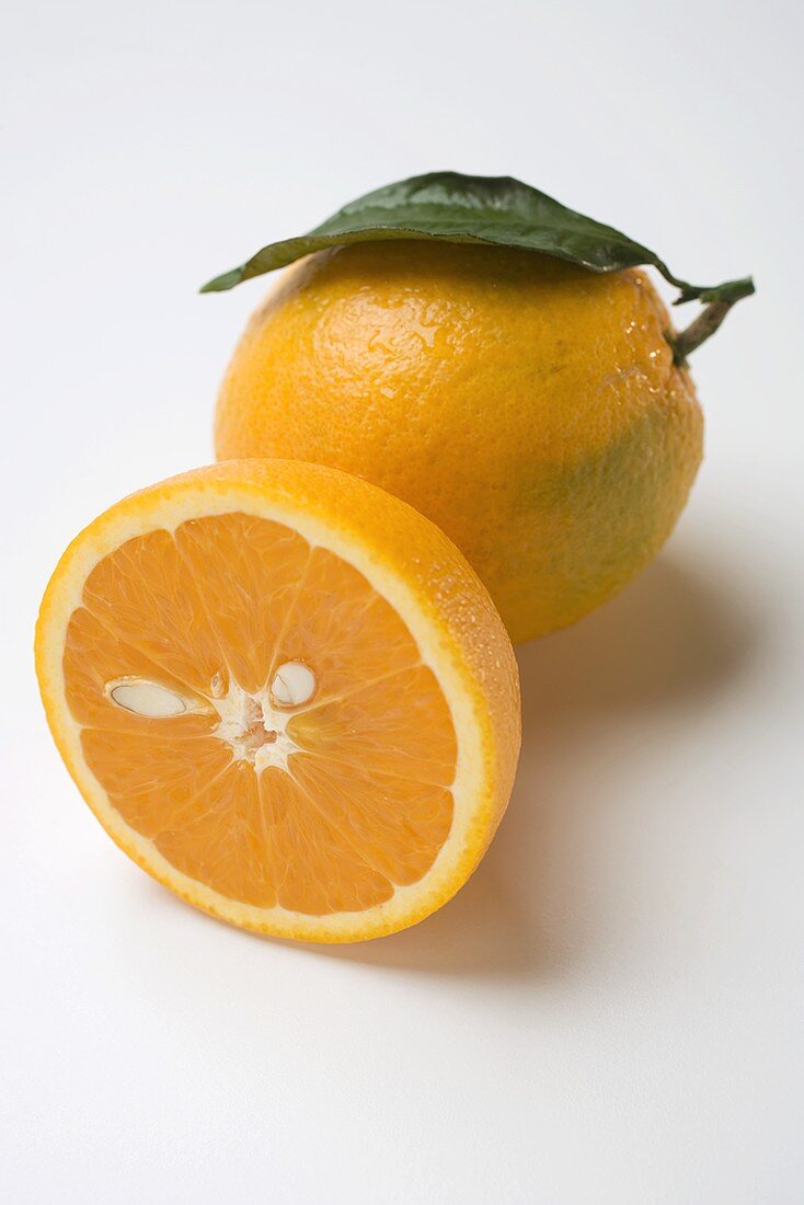 Ganze Orange mit Blatt und Orangenhälfte