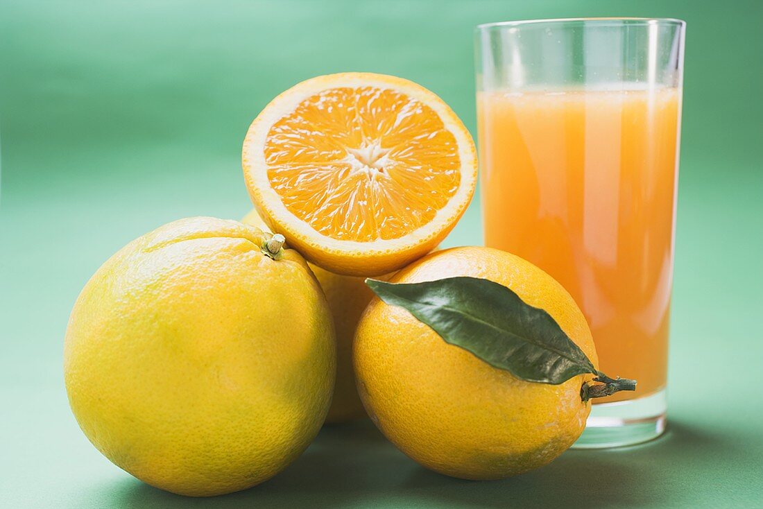Glas Orangensaft und mehrere Orangen