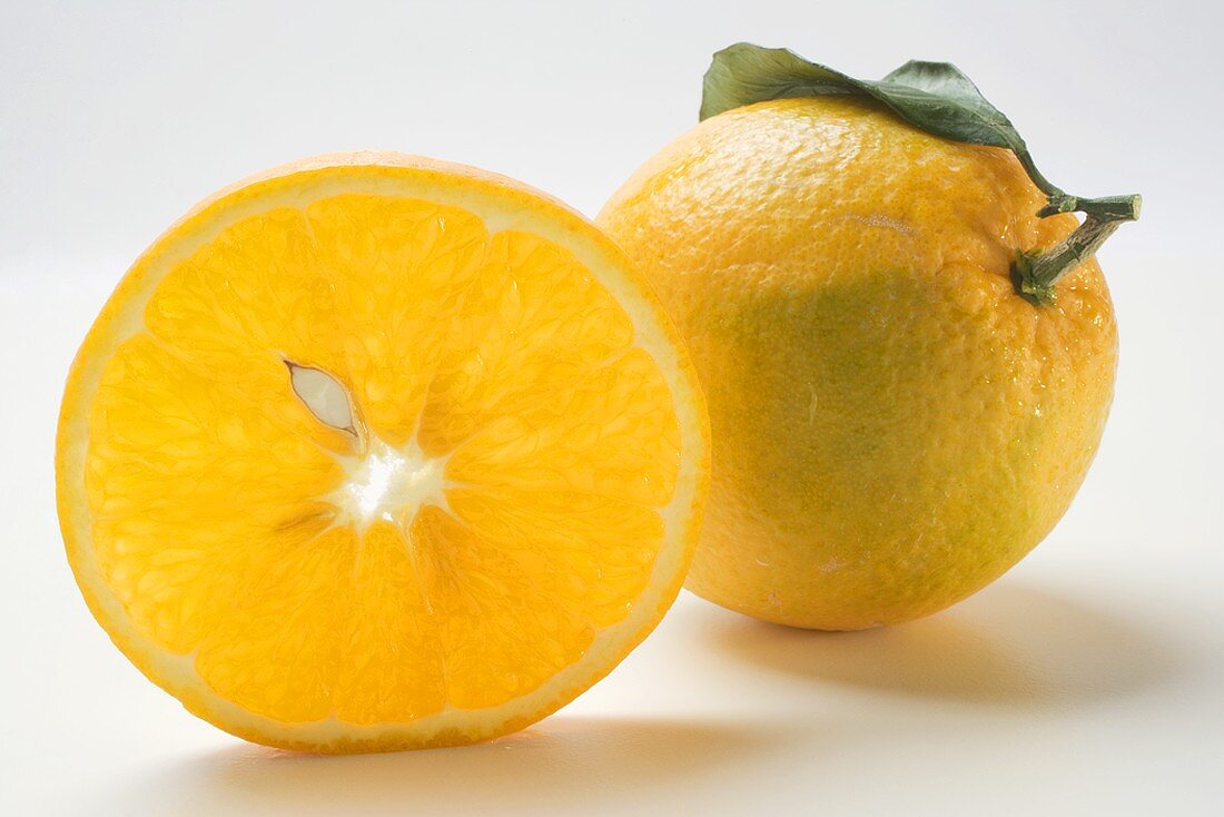 Slice of orange in front of whole orange