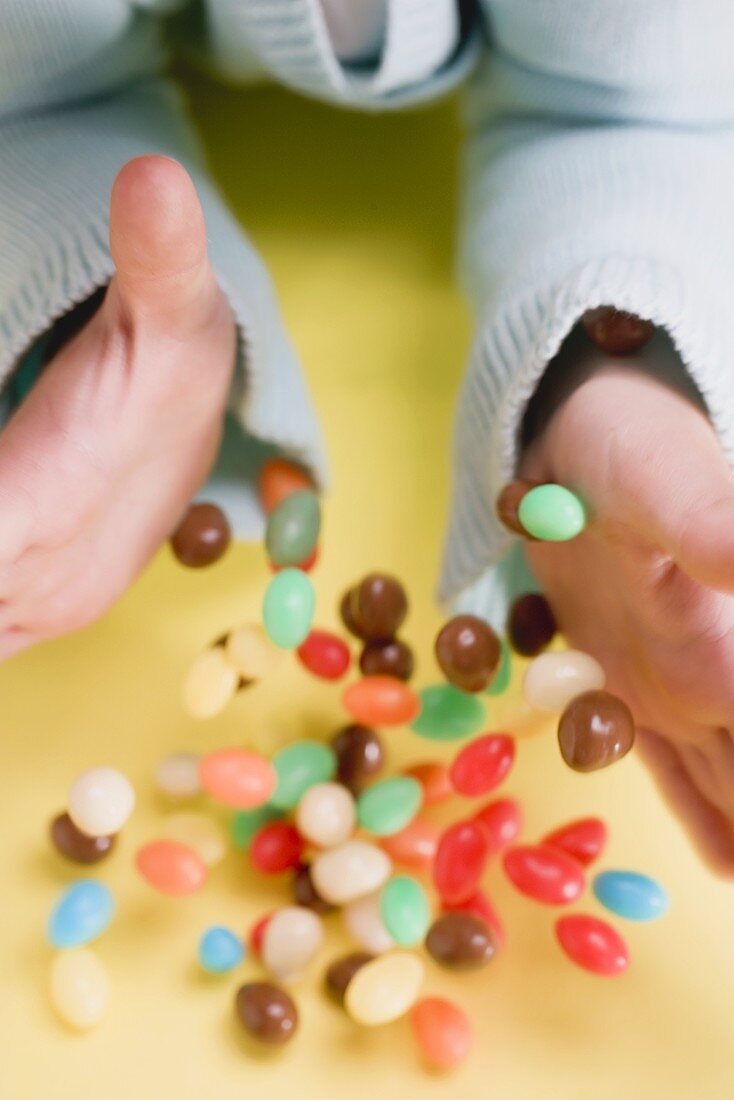 Child's hands dropping coloured sugar eggs