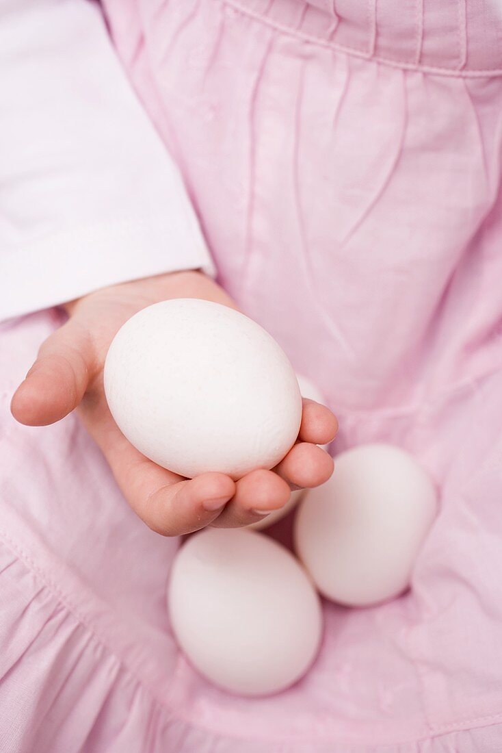 Child holding white eggs