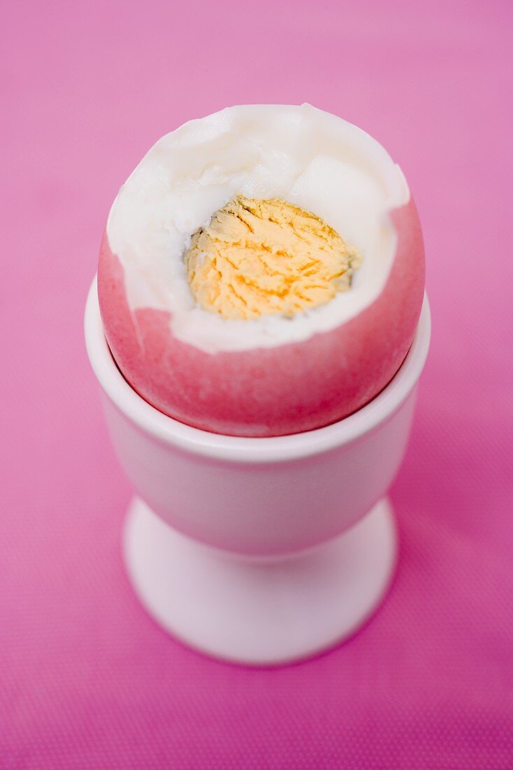 Coloured boiled egg in eggcup (with top cut off)