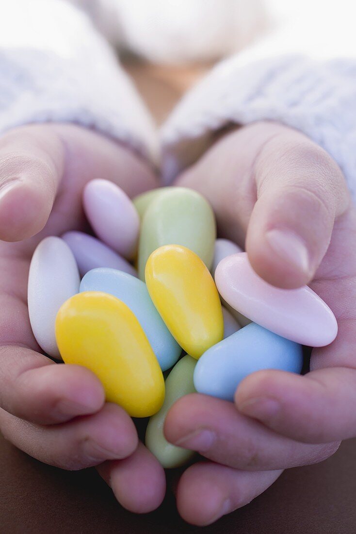 Child's hands holding sugared almonds