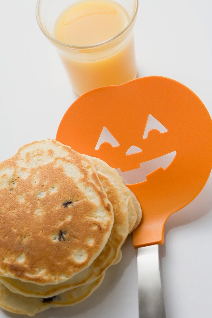 Pancakes zu Halloween mit Pfannenwender und Glas Orangensaft
