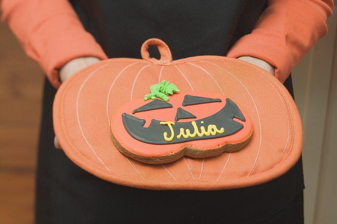 Hands holding Halloween biscuit with name on pot holder