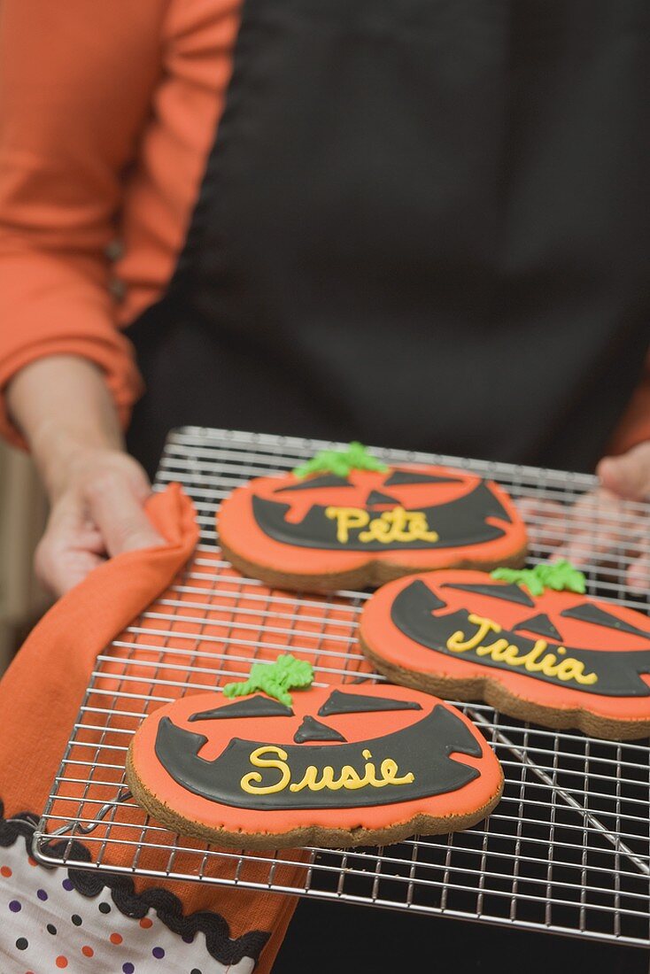 Hände halten Kuchengitter mit Namensplätzchen für Halloween