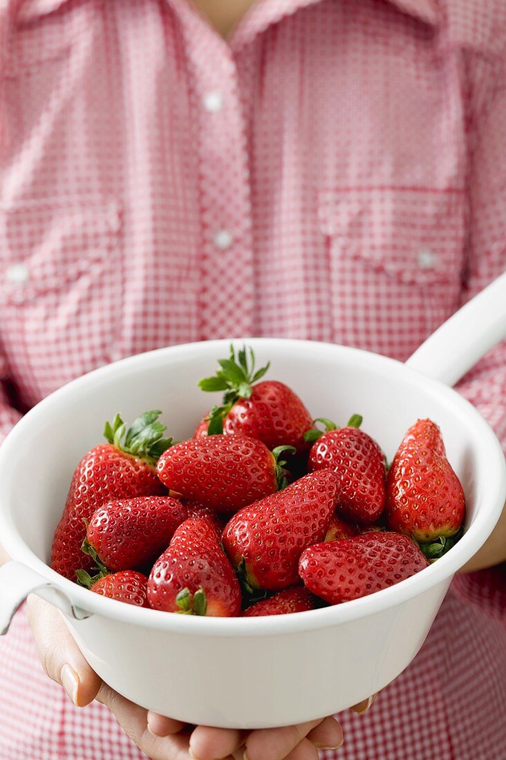 Woman holding strainer full of strawberries