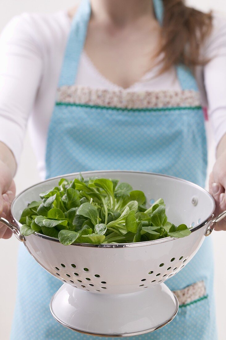 Woman holding colander full of corn salad