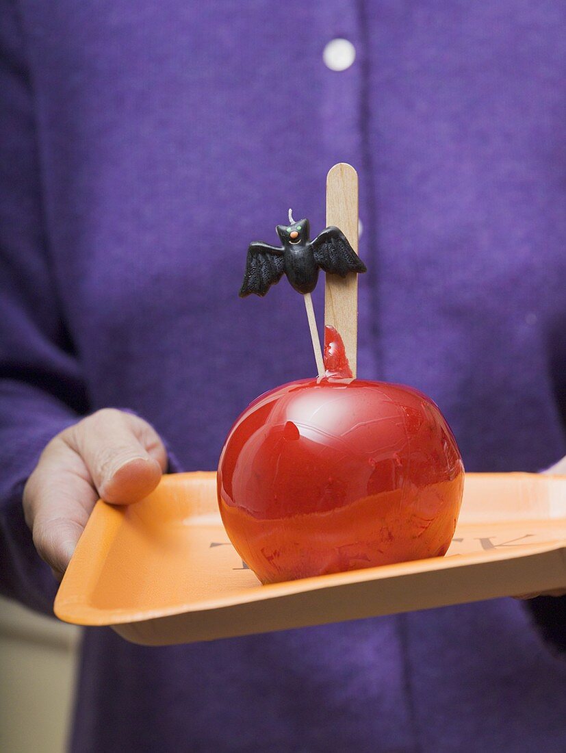 Woman holding tray of toffee apples for Halloween