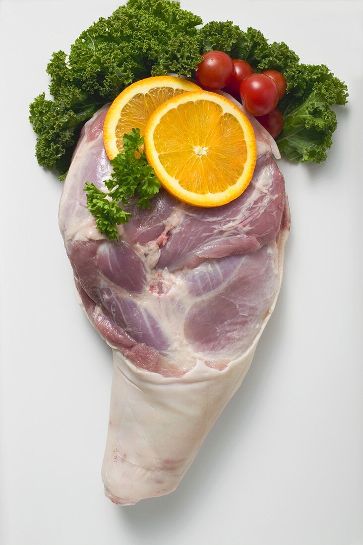 Raw knuckle of pork, garnished with orange slices