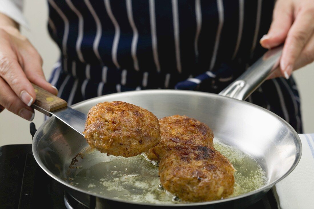 Woman frying burgers in a frying pan