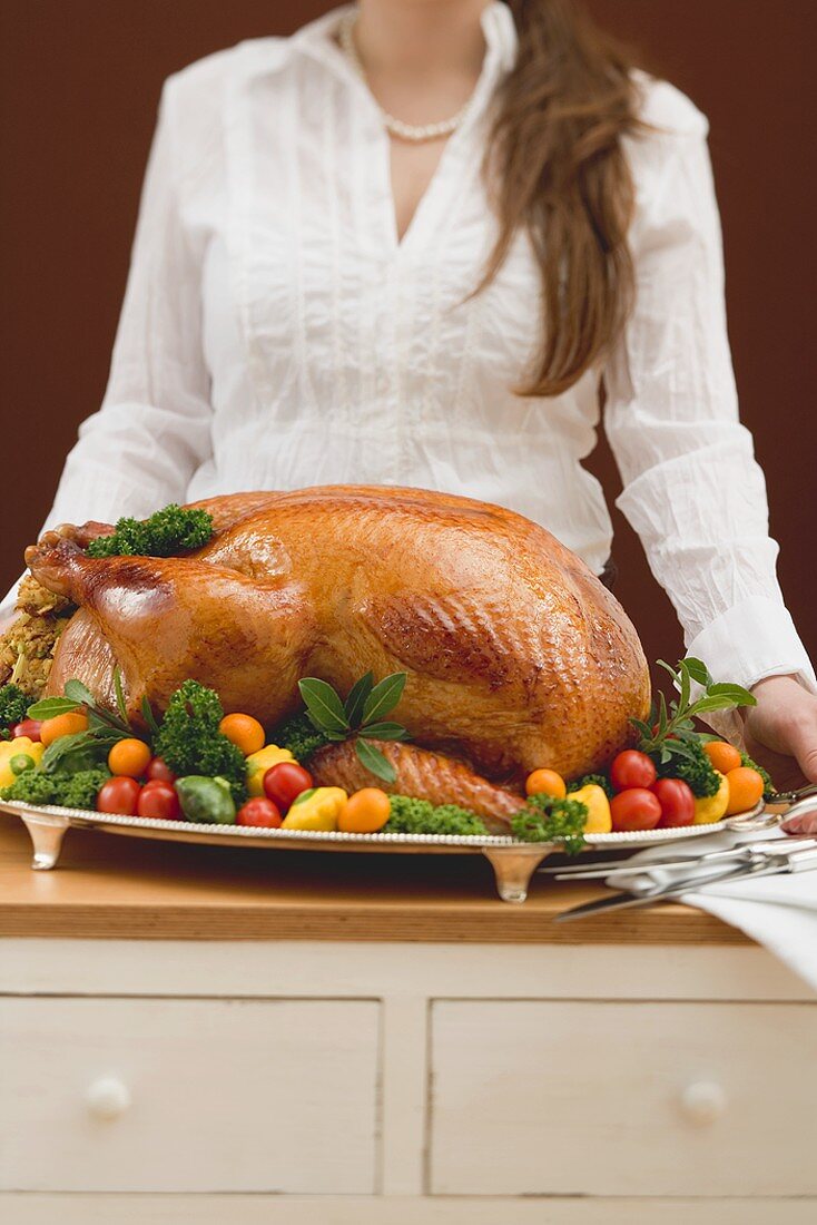 Woman holding roast turkey on large platter