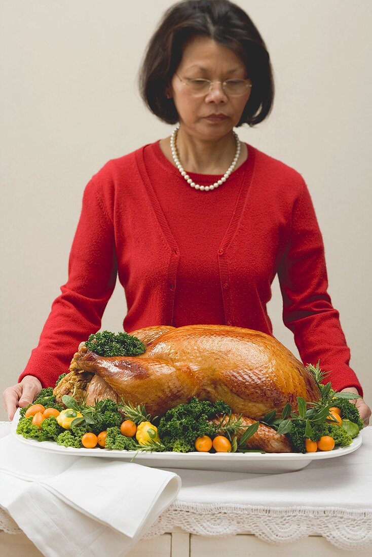Woman holding roast turkey on large platter