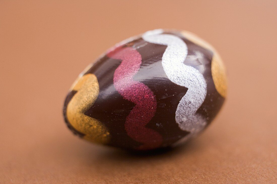 Painted chocolate egg on brown background