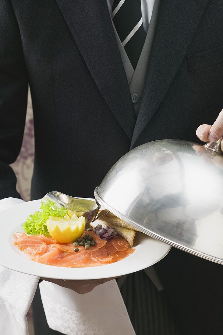 Butler serving smoked salmon with toast
