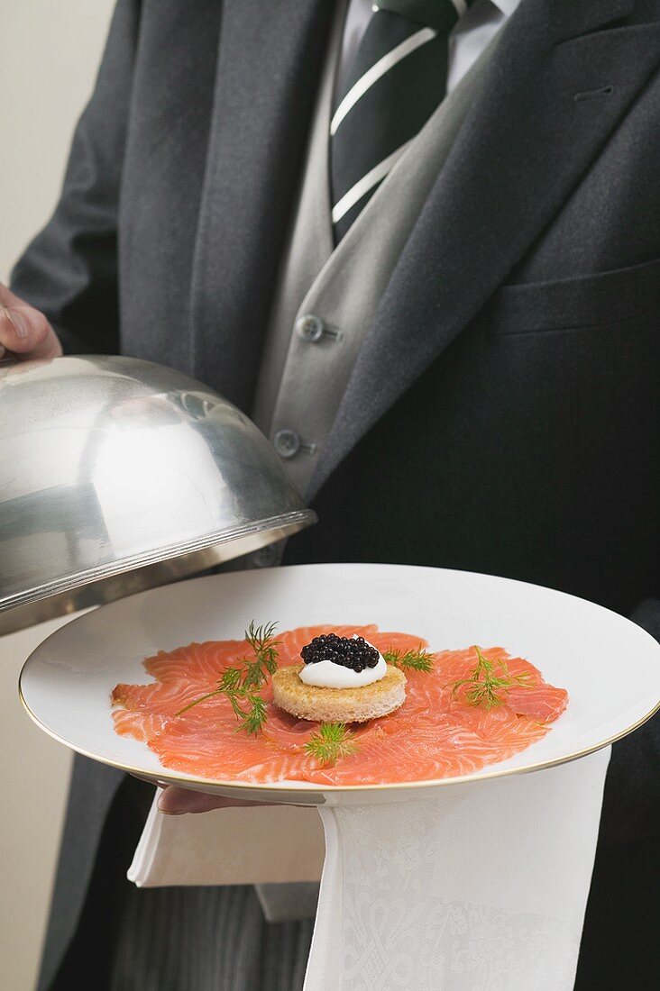 Butler serviert Räucherlachs mit Kaviar